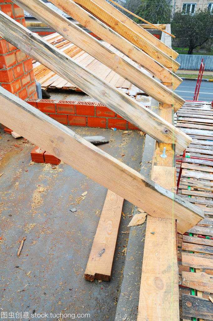 木制的屋面工程施工。房屋建筑。安装的木梁施工在房子的屋顶桁架体系。屋顶下施工。未完成的屋面施工